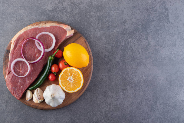 Pezzo di carne crudo e verdure fresche poste su tavola di legno  - Foto, immagini