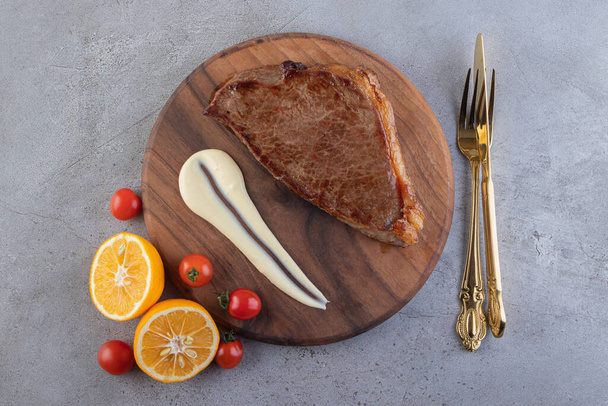 Carne jugosa con rodajas de limón y tomates cherry en la mesa. Foto de alta calidad - Foto, Imagen