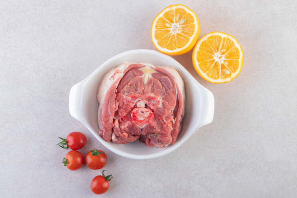 Cuenco blanco de carne cruda con tomates de limón y cereza en la mesa. Foto de alta calidad - Foto, Imagen