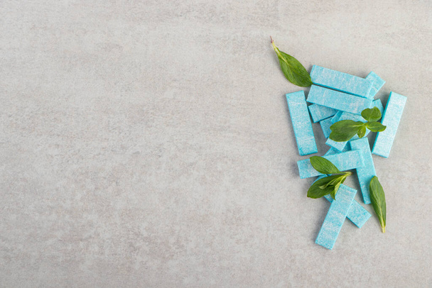 Blue chewing gums with mint leaves placed on a stone background . High quality photo - Zdjęcie, obraz