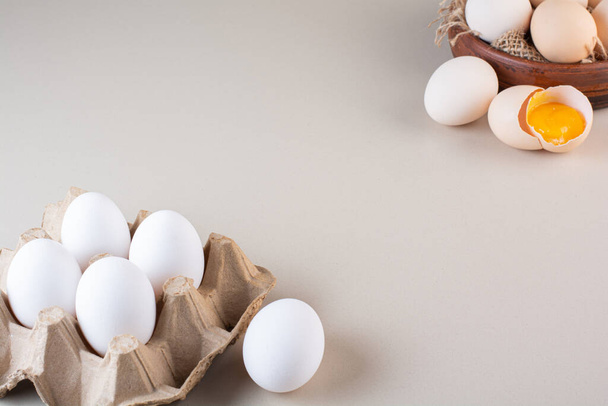 Whole and broken fresh raw eggs placed on beige table. High quality photo - 写真・画像