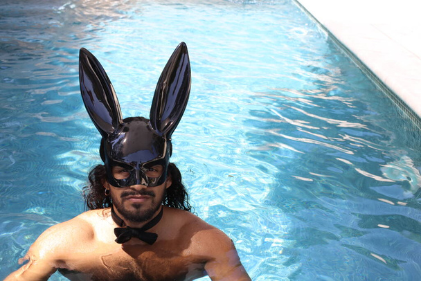 lähikuva muotokuva komea nuori sekoitettu rotu paidaton mies pupu naamio uima-altaassa - Valokuva, kuva