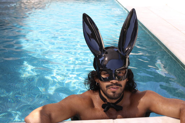 zblízka portrét pohledné mladé smíšené rasy bez košile muž s králičí maskou v bazénu - Fotografie, Obrázek