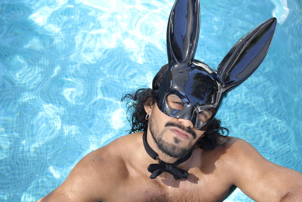 крупним планом портрет красивого молодого змішаного чоловіка без сорочки з маскою кролика в басейні
 - Фото, зображення