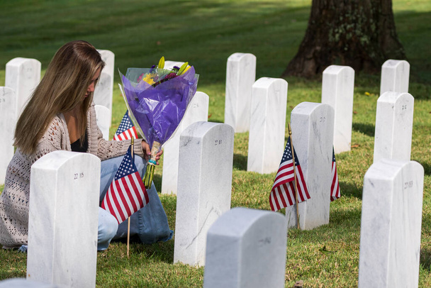 Uma jovem noiva mostra sua dor no local do enterro de um membro da família em um cemitério militar - Foto, Imagem