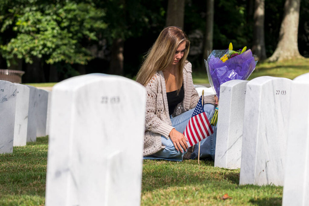 Une jeune mariée montre son chagrin au lieu de sépulture d'un membre de sa famille dans un cimetière militaire - Photo, image