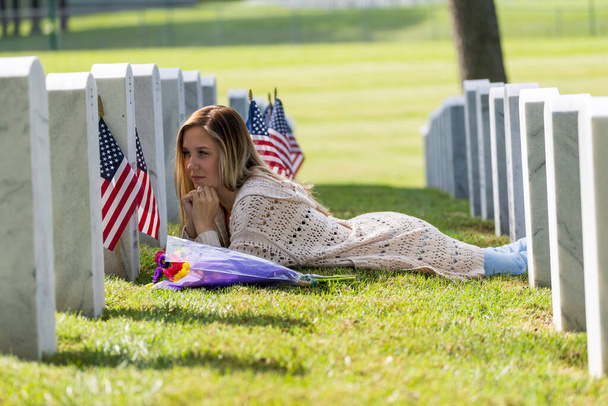 Une jeune mariée montre son chagrin au lieu de sépulture d'un membre de sa famille dans un cimetière militaire - Photo, image