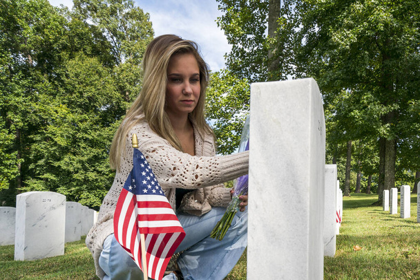 Młoda panna młoda okazuje smutek na cmentarzu wojskowym, na cmentarzu pochówku członka rodziny. - Zdjęcie, obraz