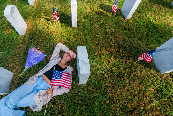 Μια νεαρή νύφη δείχνει τη θλίψη της στον τόπο ταφής ενός μέλους της οικογένειας σε στρατιωτικό νεκροταφείο. - Φωτογραφία, εικόνα