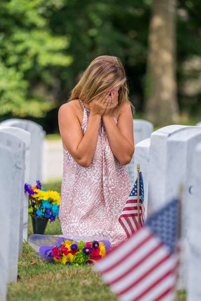若い花嫁は軍事墓地の家族の埋葬場所で彼女の悲しみを示しています - 写真・画像