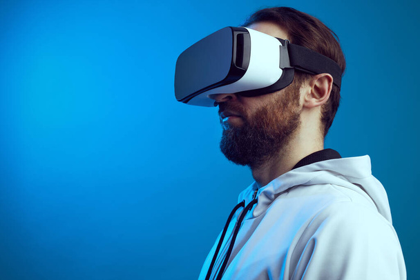 Boční pohled seriózního chlapa ve VR headsetu, který zažívá jiný svět ve studiu - Fotografie, Obrázek