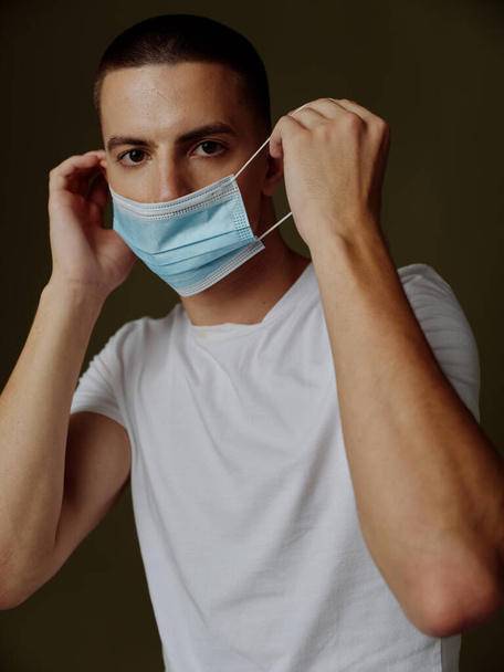muž na sobě lékařské masky bílé tričko tmavé pozadí oříznuté pohled covid pas - Fotografie, Obrázek