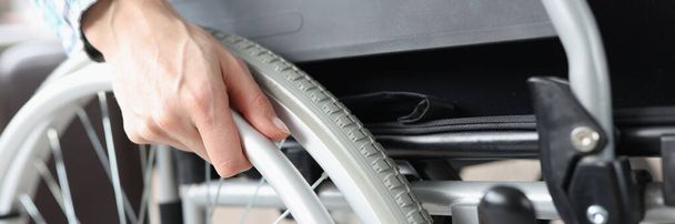 Disabled woman sitting in wheelchair and holding on to wheel closeup - Fotoğraf, Görsel