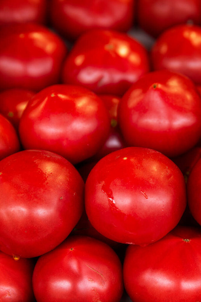 There are many ripe juicy red tomatoes on the market counter. Health and vitamins from nature. Close-up. Vertical. - Photo, Image