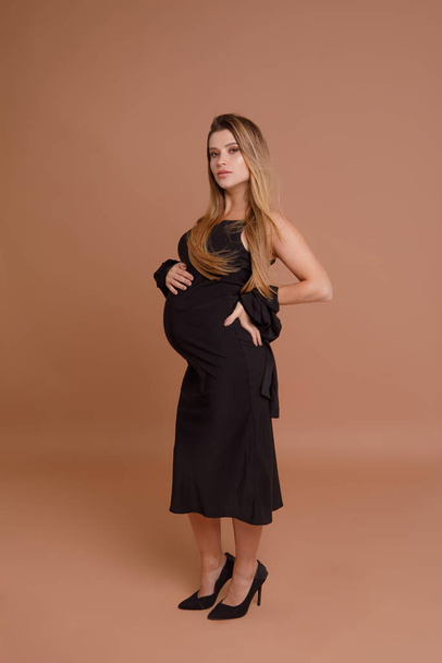 беременная женщина в студии на бежевом фоне - Фото, изображение