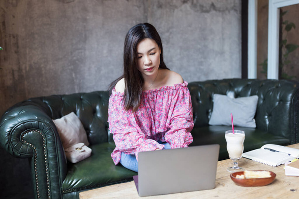 Pretty young asian business woman using laptop in modern cafe.  - Foto, immagini