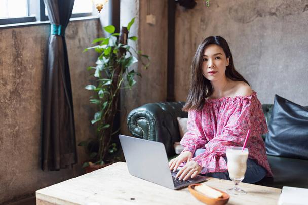 Pretty young asian business woman using laptop in modern cafe.  - Zdjęcie, obraz