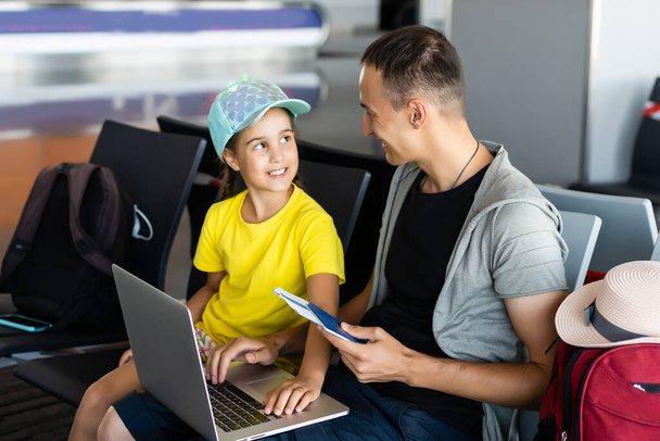 Όμορφος νεαρός πατέρας και η μικρή κόρη χρησιμοποιώντας φορητό υπολογιστή στο αεροδρόμιο - Φωτογραφία, εικόνα