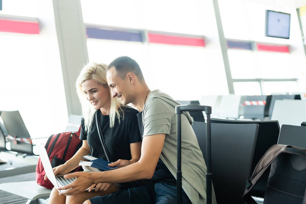 Smart Working und digitaler Nomade. Alternatives Bürokonzept mit ein paar kaukasischen Menschen, die während einer Flugreise im Flughafen Mobiltelefone und Laptops benutzen. - Foto, Bild