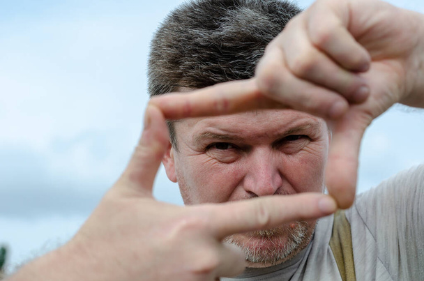 Портрет дорослого чоловіка, що робить рамку з його пальців. A-гра
 - Фото, зображення