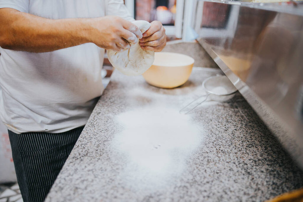 A closeup shot of a male cook preparing dough in a restaurant kitchen - Foto, immagini