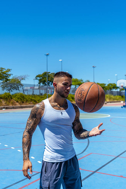 A vertical shot of a sporty Caucasian male with tattoos playing basketball - 写真・画像