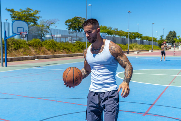 A view of a sporty Caucasian male with tattoos playing basketball - Foto, Imagem