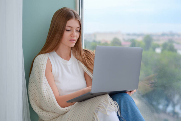 Молодая деловая женщина занимается бумажной работой и работает над ноутбуком за своим столом в офисе - Фото, изображение
