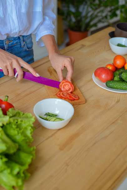 Close up photo of young female hands preparing wonderful fresh vegan salad in kitchen at home - Photo, Image