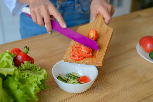 Close up photo of young female hands preparing wonderful fresh vegan salad in kitchen at home - Foto, Imagem