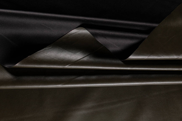 oppervlak van kunstleer met plooien voor het naaien van kleding in kaki kleur - Foto, afbeelding