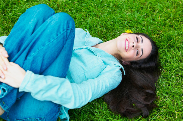 beautiful young woman lying on green grass in park - Foto, immagini