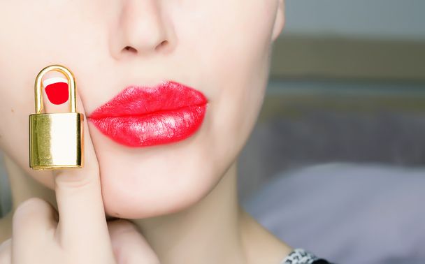 Woman with red lips holding gold lock - Foto, afbeelding