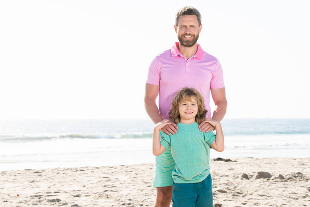 οικογενειακό πορτραίτο ευτυχισμένου πατέρα και γιου σε καλοκαιρινή παραλία, φωτοτυπικός χώρος, οικογένεια - Φωτογραφία, εικόνα