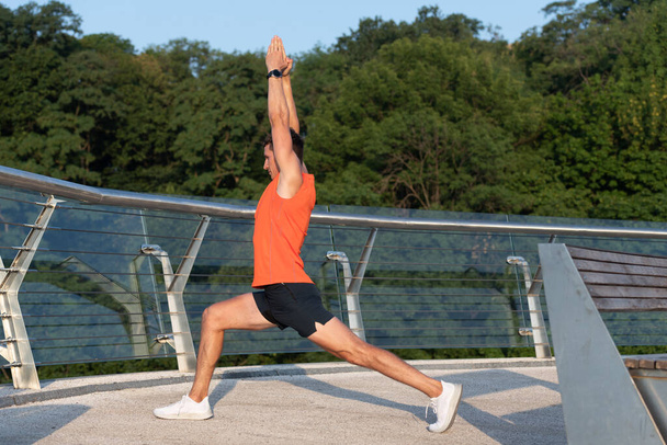 Feel the stretch in your hip. Man do crescent lunge stretch raising arms. Doing yoga or pilates exercise - Photo, Image