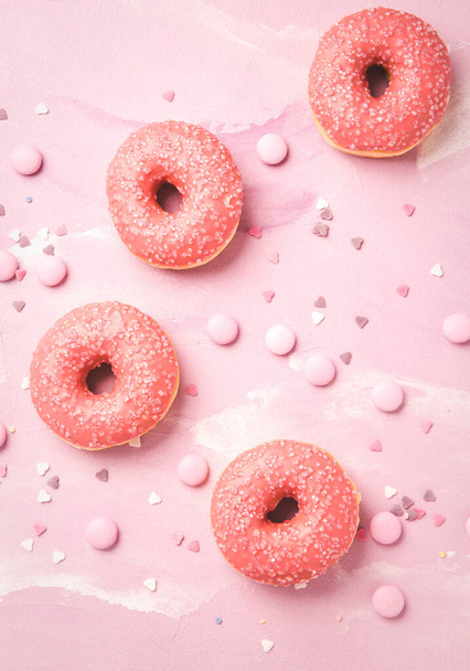 Rózsaszín cukormázas fánkok és rózsaszín csokoládé bab rózsaszín alapon - Fotó, kép