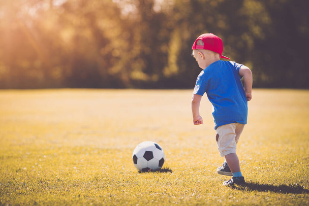 Little boy playting football on the field with gates. Active child in summer with ball - Φωτογραφία, εικόνα