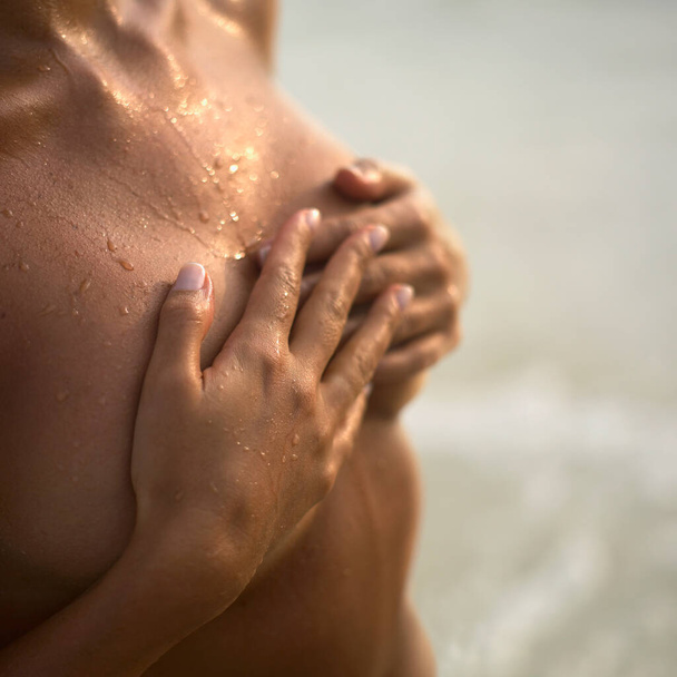 Mid section view of a young woman covering her breast with her hands - Foto, Imagem