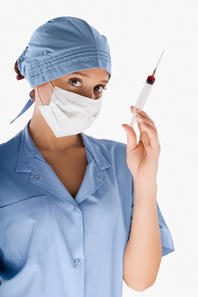 young woman doctor with syringe and mask on white background - Foto, Bild