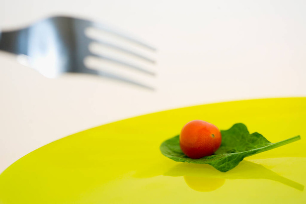 Close-up of a cherry tomato with a spinach leaf on a plate - Foto, Imagen