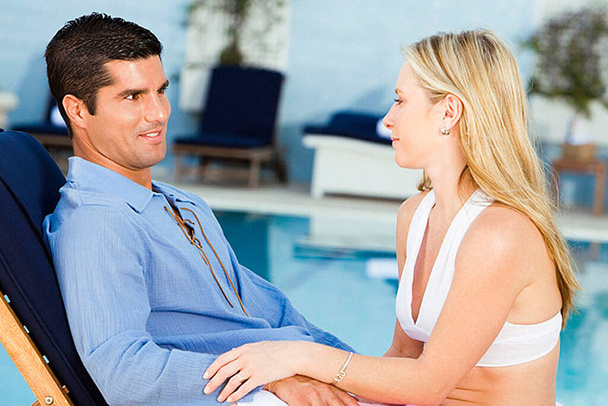 Mujer joven y un hombre adulto medio sentado junto a la piscina
 - Foto, Imagen