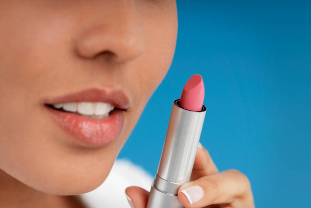 Close-up of a young woman holding a lipstick - Foto, Bild