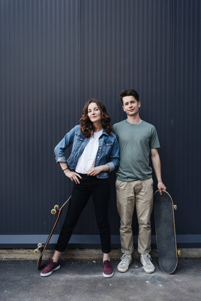 Moderna coppia sorridente in piedi insieme con skateboard - Foto, immagini