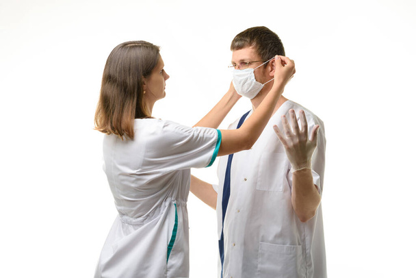 The nurse puts a medical mask on the doctor's face - Φωτογραφία, εικόνα