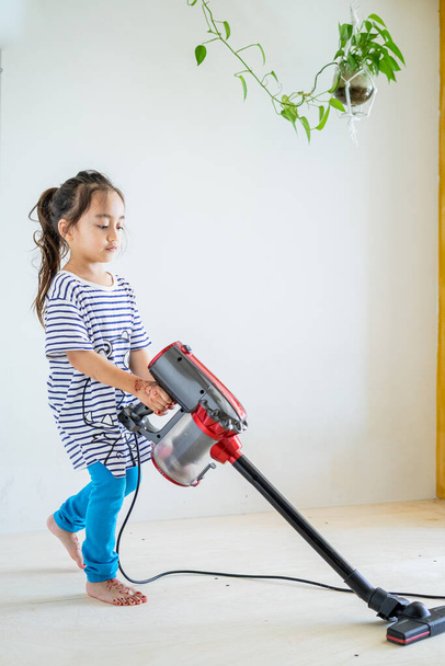 Linda niña limpieza piso de madera con aspiradora - Foto, Imagen