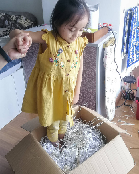 Un niño no identificado está de pie dentro de la caja de papel rallado para comprimirla. Papel de reciclaje. - Foto, Imagen