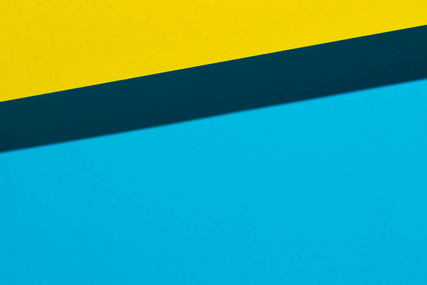 the shadow formed by a sheet of yellow paper on a blue surface - Foto, Bild