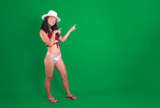 Menina asiática de biquíni, apontando para algo ao lado dela, sorrindo na chave chroma - Foto, Imagem