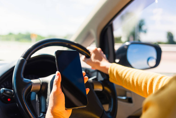 Asian woman inside a car and using a hand holding mobile smartphone blank screen while driving the car in the morning during going to work on highway, Transportation and vehicle concept - Foto, afbeelding