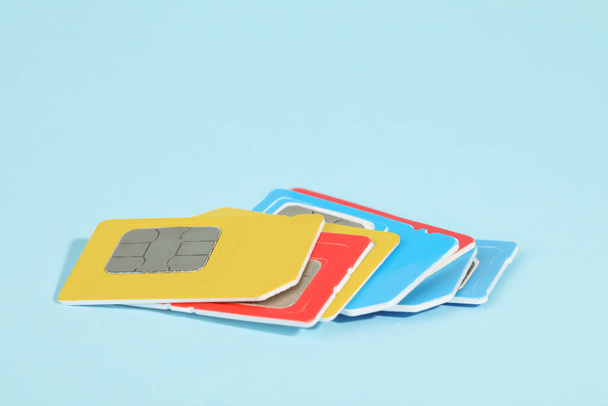 Different SIM cards on light blue background, closeup - Fotó, kép